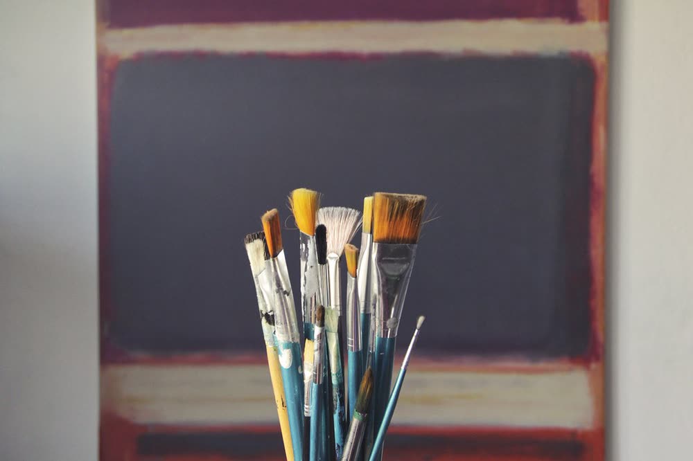 Pinceles de artista frente a un cuadro colorido en el estudio