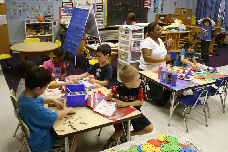 Maestra y niños trabajando en manualidades en un salón de clases